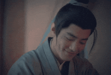 a man in a kimono is smiling and looking down at something