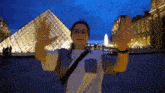 a woman standing in front of a pyramid with her arms outstretched .