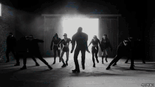a group of people are dancing in a dark room with a light coming through the door and a watermark that says 44