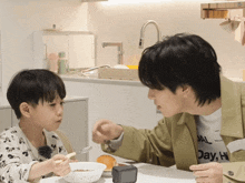 a man and a boy are sitting at a table eating cereal and the boy is wearing a shirt that says day