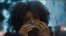 a man with curly hair is eating a hamburger in a dark room .