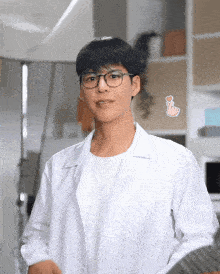 a young man wearing glasses and a lab coat has a heart shaped sticker on his chest