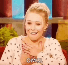 a woman is smiling and holding her hands to her chest while saying omg .