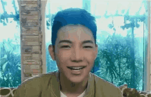 a man with blue hair is smiling and looking at the camera