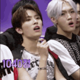 a group of young men are sitting in a row and one of them is wearing a bracelet with the number 1040 on it .