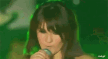a woman is singing into a microphone on a stage .