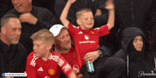 a young boy wearing a snapdragon shirt is being held up by a man