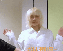 a woman with blonde hair is wearing a white shirt and necklace