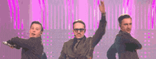 three men in suits and glasses are performing on a stage .