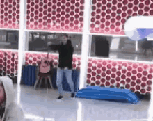 a man is dancing in a room with a red and white wall .