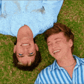 two young men are laying on their backs on the grass and smiling