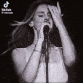 a woman singing into a microphone with a tattoo on her hand