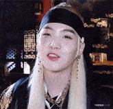 a close up of a person wearing a costume with a headband and earrings .