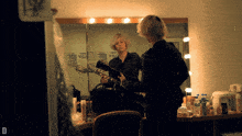 a person playing a guitar in front of a mirror with the letter d on the bottom right