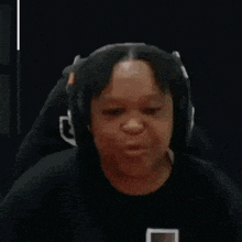 a person wearing headphones and a twitch shirt is sitting in a chair .