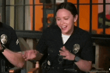 a woman in a police uniform is sitting in a chair and laughing .