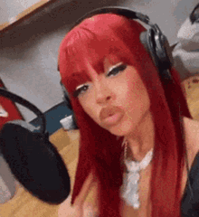 a woman with long red hair is wearing headphones and a necklace .