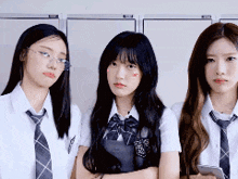 three girls in school uniforms and ties are standing next to each other in a locker room .