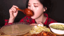 a woman is eating food with a wooden spoon in her mouth
