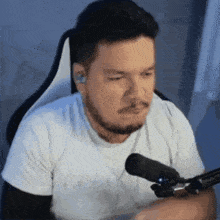 a man with a beard is sitting in front of a microphone and making a funny face .