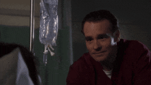 a man in a red scrub is smiling in front of an iv