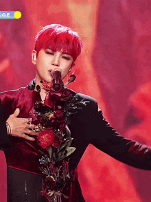 a man with red hair is singing into a microphone while holding a bouquet of flowers around his neck