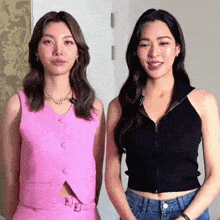 two women are standing next to each other in a room wearing different outfits .