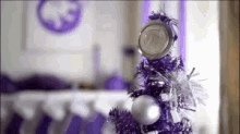 a purple christmas tree with silver decorations and a medal on top