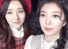 two girls are posing for a picture and one has a red hat on