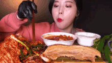 a woman is eating food with chopsticks while wearing gloves .