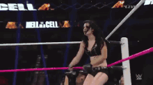 a woman is standing in a wrestling ring with a referee standing behind her .