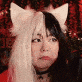 a woman wearing a cat ear wig and a choker is making a funny face .