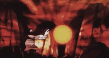 a cartoon character is standing in front of a large orange ball in a dark room .