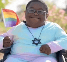 a person in a wheelchair holding a rainbow flag and a star necklace