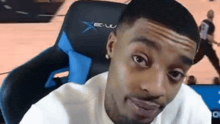 a man is sitting in a blue and black gaming chair and looking at the camera .