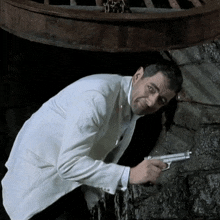 a man in a white suit is holding a gun in his right hand