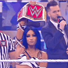 a woman in a wrestling ring holds a wwe championship belt above her head