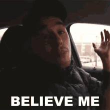 a man in a car says " believe me " in white letters