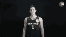 a man in a corinthians jersey smiles in front of a black background