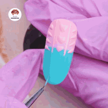 a pink glove is holding a nail with a pink and blue sweater design on it