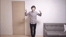 a man in a plaid shirt is holding a remote control in front of a couch