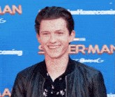 a man in a leather jacket is smiling on a red carpet .