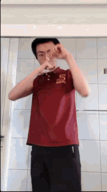 a man in a red shirt is brushing his teeth in a bathroom