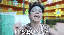a woman wearing a sun visor and a leopard print shirt is saying it 's bunny .