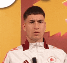 a man in a white adidas jacket is holding a microphone .