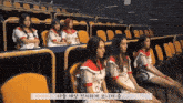 a group of girls are sitting in an auditorium with korean writing on the bottom left