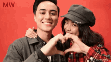 a man and woman make a heart shape with their hands