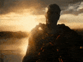 a painting of a man standing in front of a body of water with the sun shining through the clouds