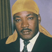 a man in a suit and tie wears a yellow head scarf