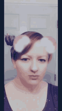 a woman taking a selfie with a bun in her hair and pink ears on her face